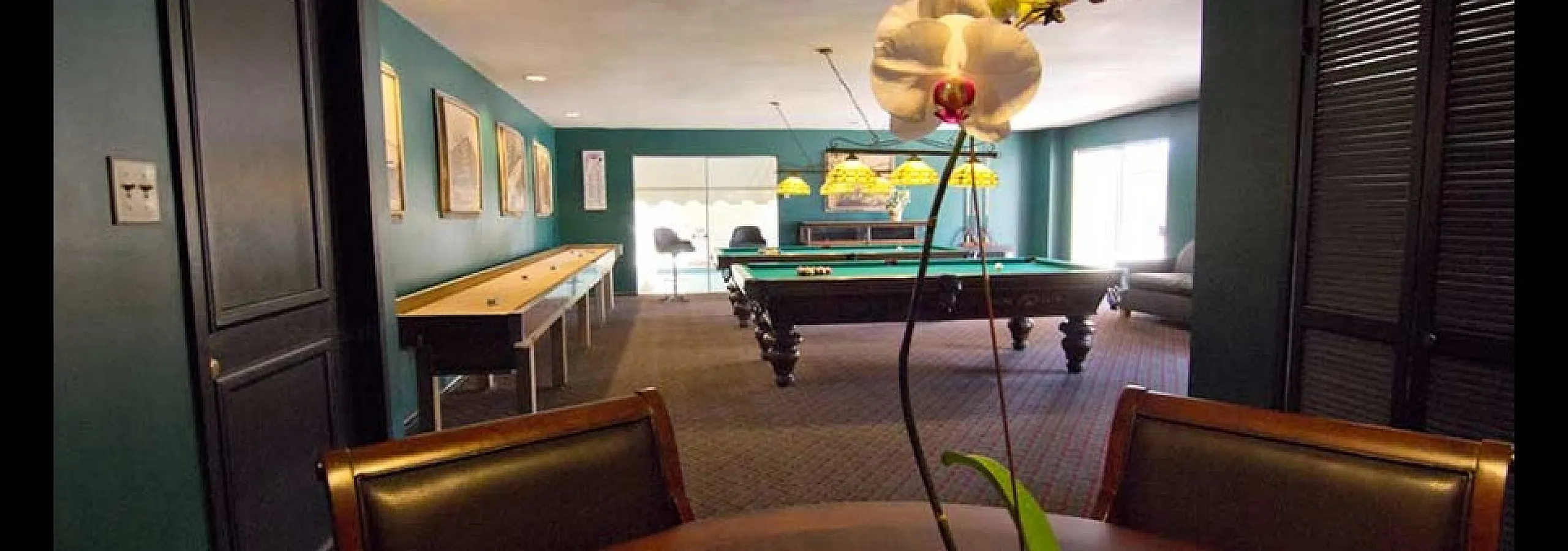 Chic recreational room featuring a stylish pool table, shuffleboard, and elegant decor with vibrant accents, perfect for entertainment.