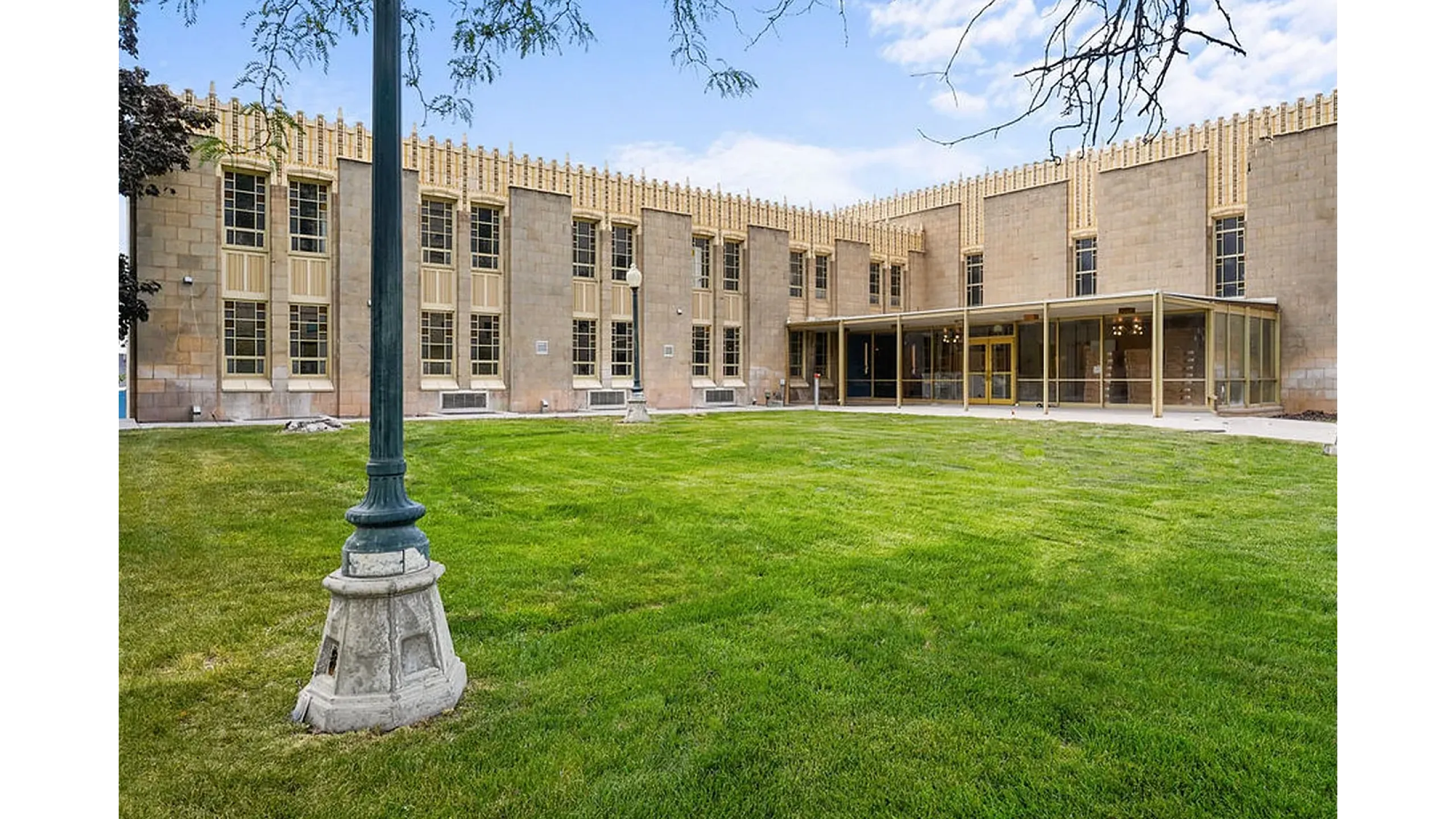 Historic architectural building with large windows and lush green lawn, surrounded by serene outdoor ambiance.