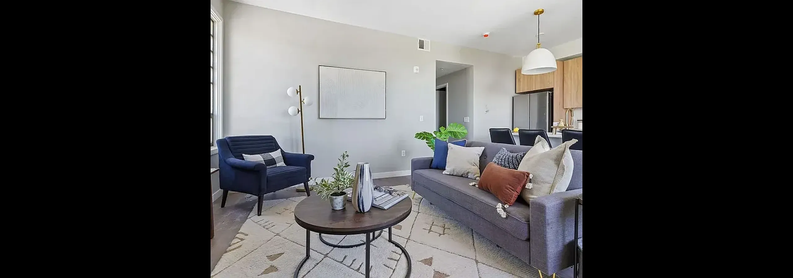 Bright and modern living room with high ceilings, featuring a stylish sofa, elegant armchairs, and tall stained-glass windows.