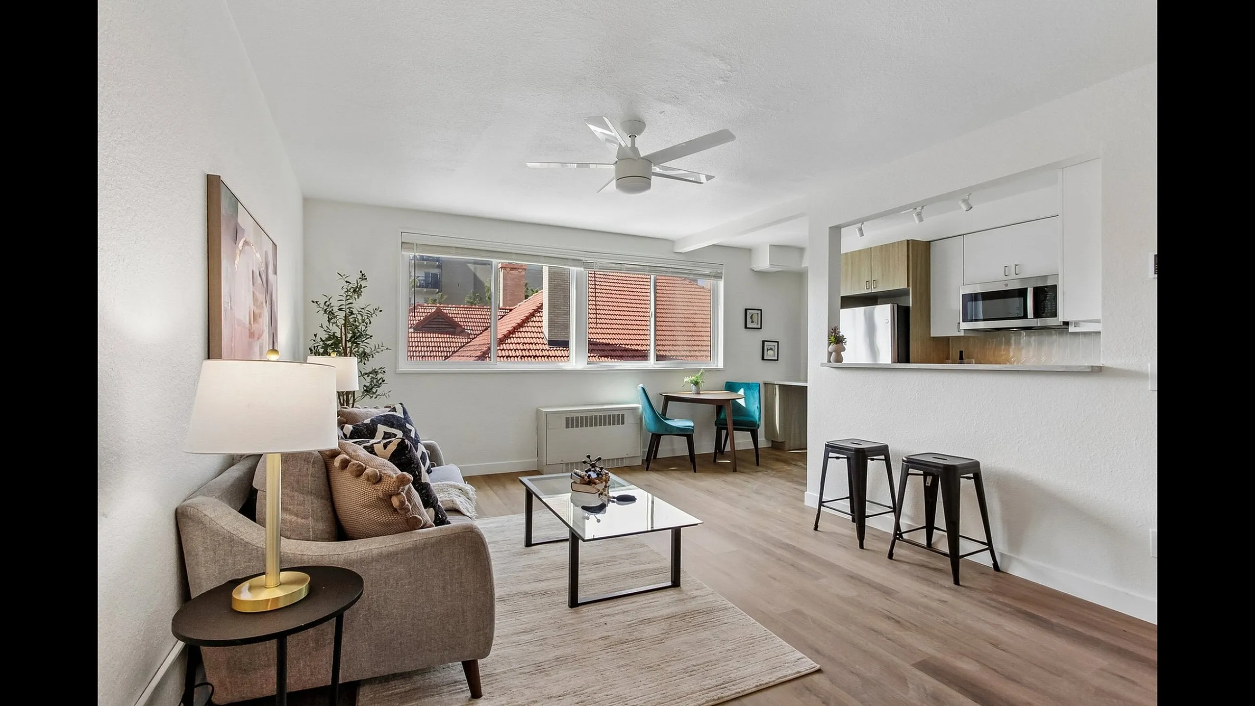Modern open-concept living room with cozy seating, large windows offering abundant natural light, and a sleek adjoining kitchen with contemporary decor.
