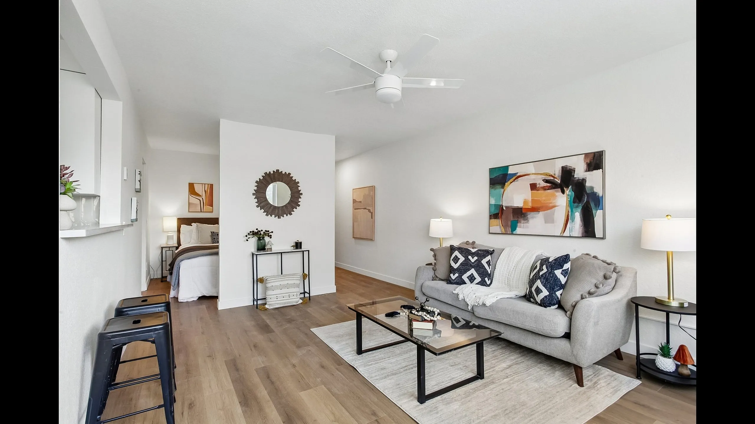 Modern apartment living room with stylish decor, featuring a cozy grey sofa, abstract wall art, and elegant lighting.
