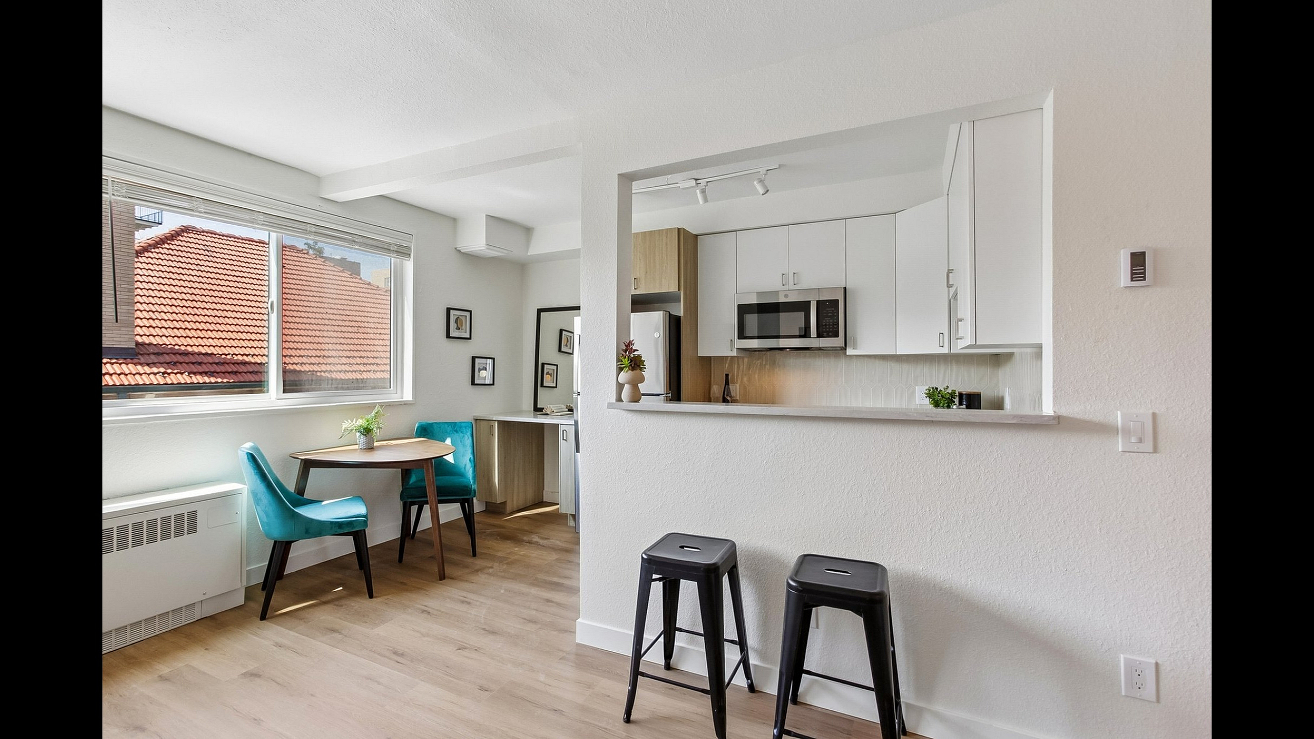 Inviting open-concept living space with a modern kitchen, cozy dining area, and sleek bar stools, filled with natural light.