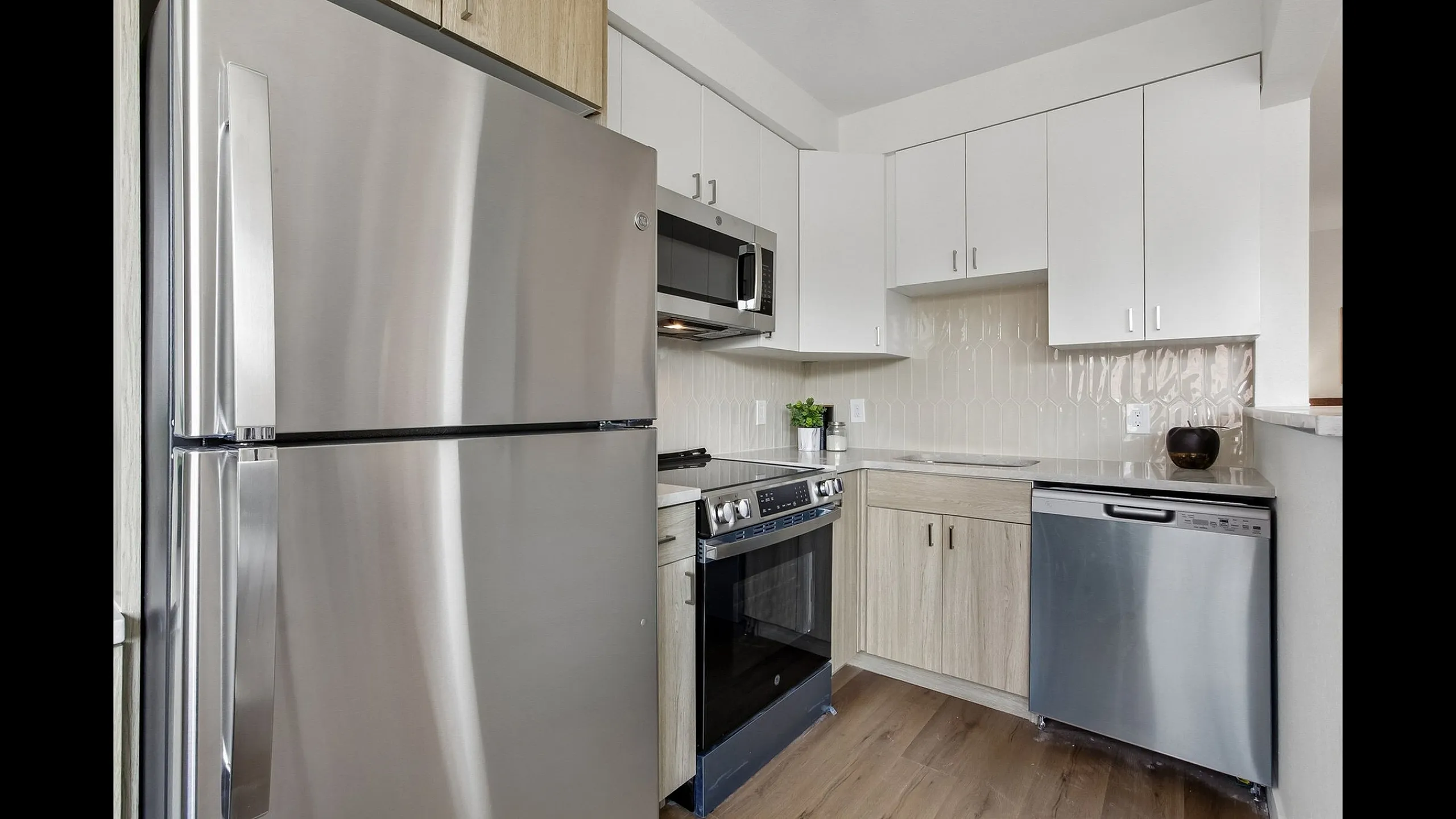Contemporary kitchen with stainless steel appliances, natural wood cabinetry, and elegant backsplash.