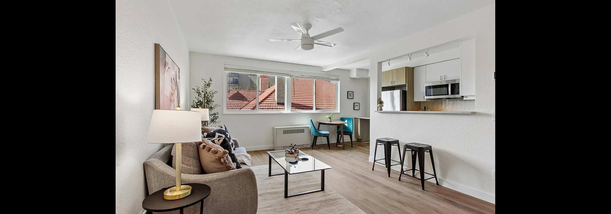 Bright and modern living room with stylish decor, open layout, and charming dining nook, featuring large windows and a sleek kitchen bar.