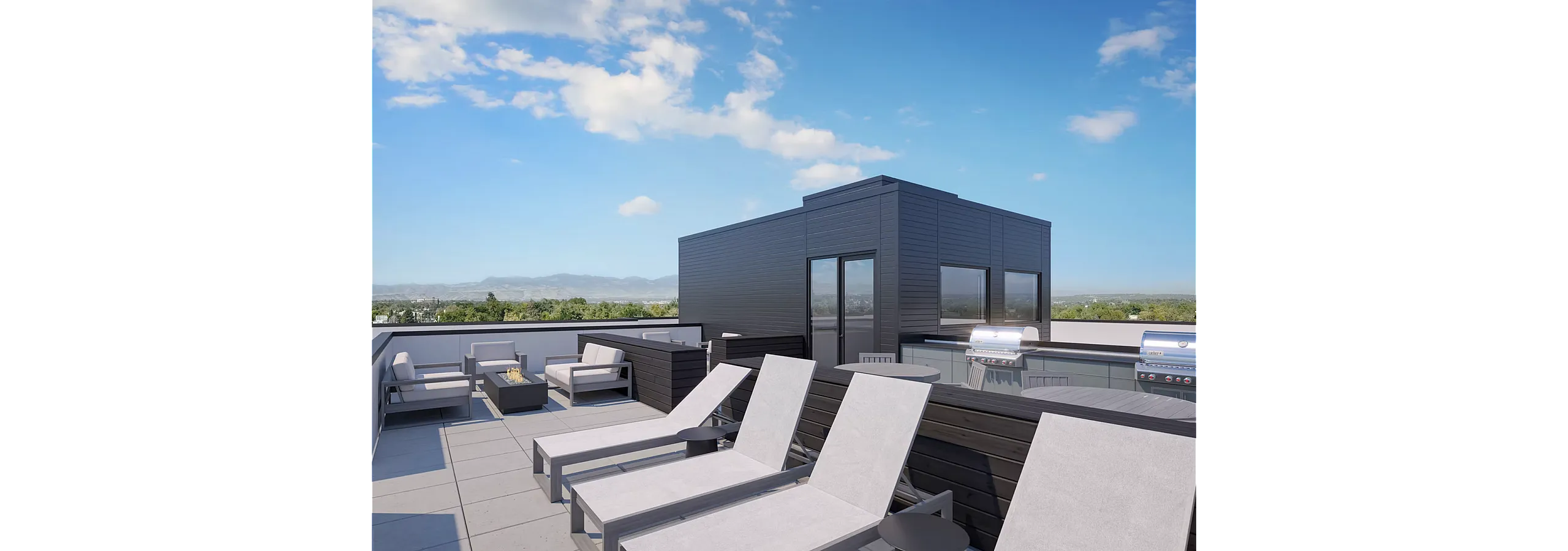 Luxurious rooftop patio with sleek lounge chairs, a modern fire pit, and built-in grills against a stunning mountain backdrop.