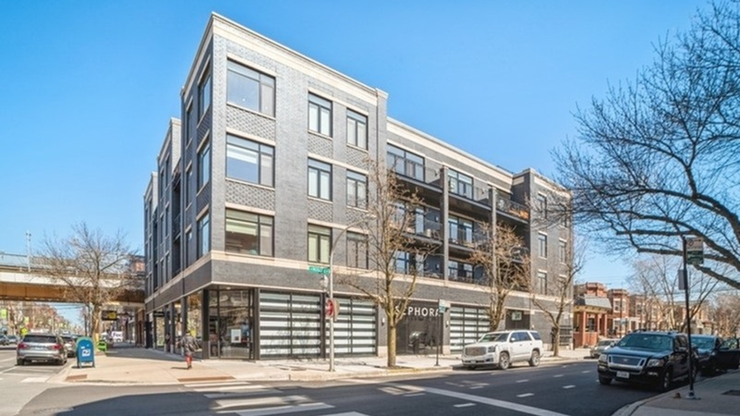 Chic urban apartment building with modern design, situated on a vibrant city corner with easy access to local amenities.