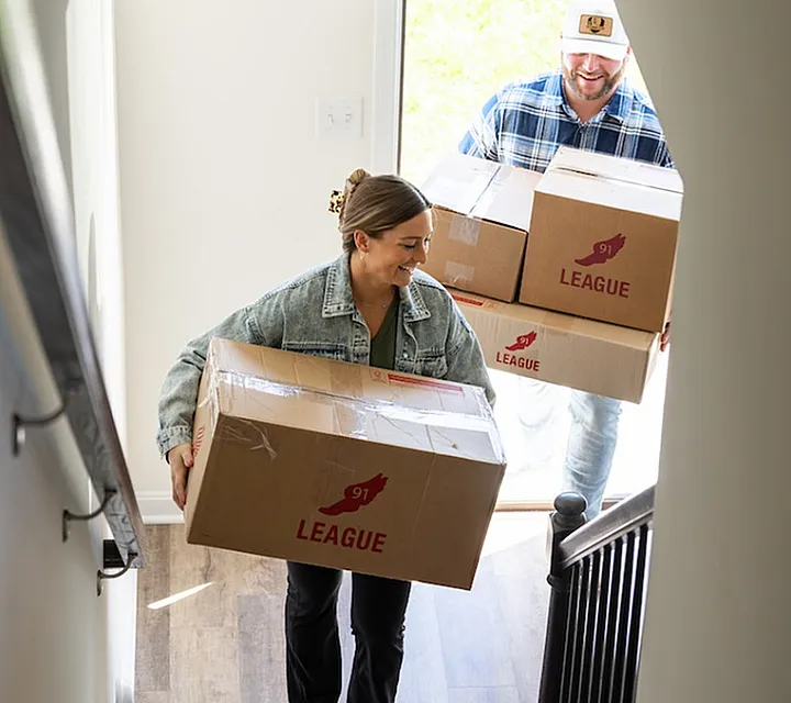 Couple carrying moving boxes up a staircase in their new home, symbolizing a fresh start.