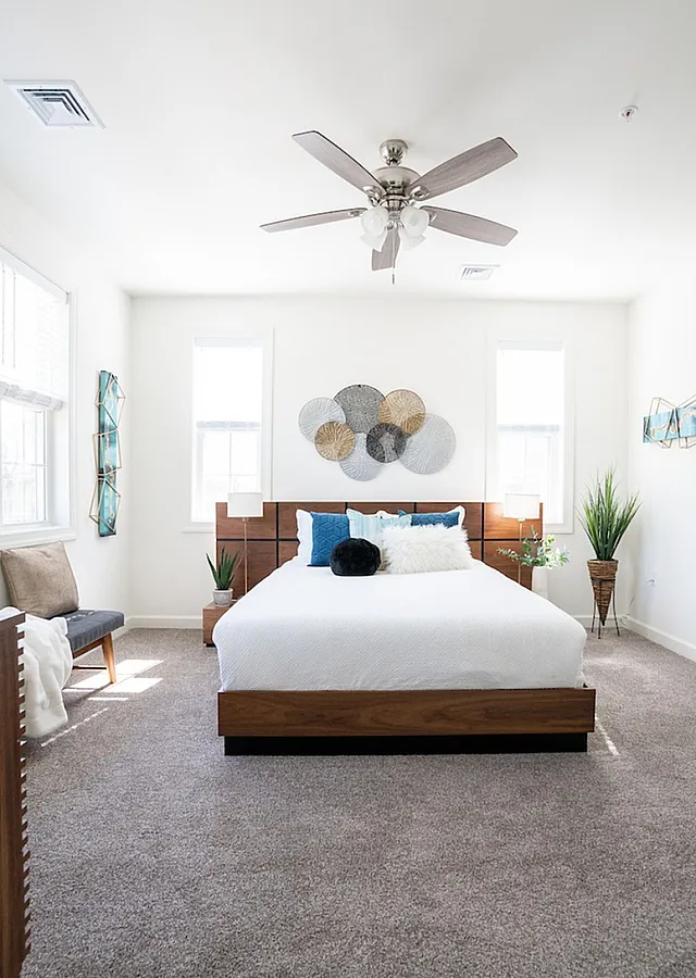 Spacious and modern bedroom with plush carpet, stylish wooden bed frame, and decorative wall art.