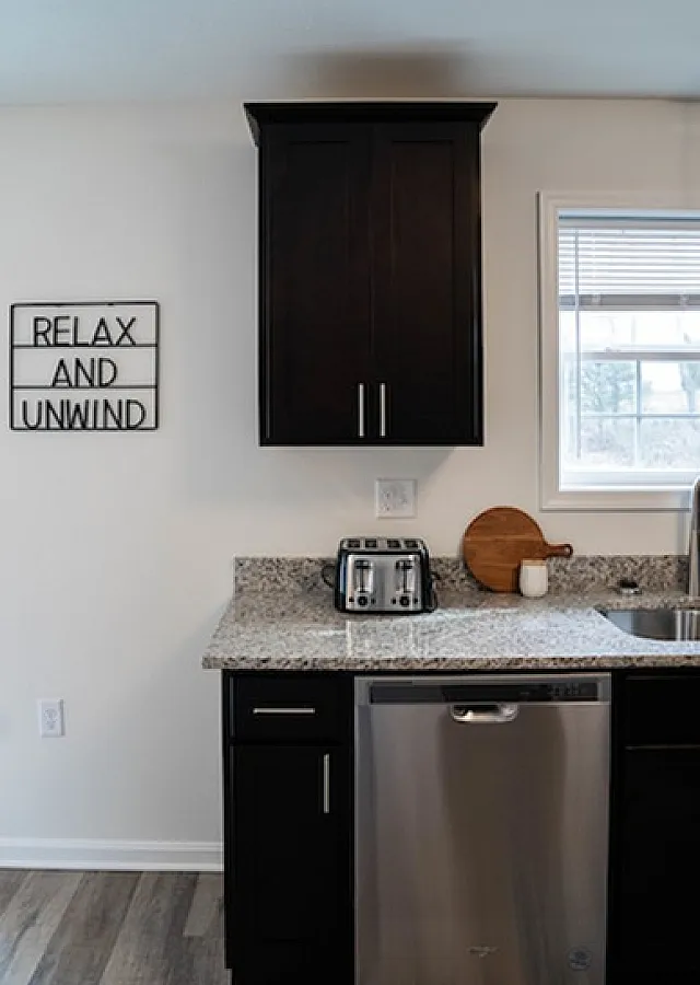 Inviting kitchen space featuring modern dark cabinets, granite countertops, and a stainless steel dishwasher.