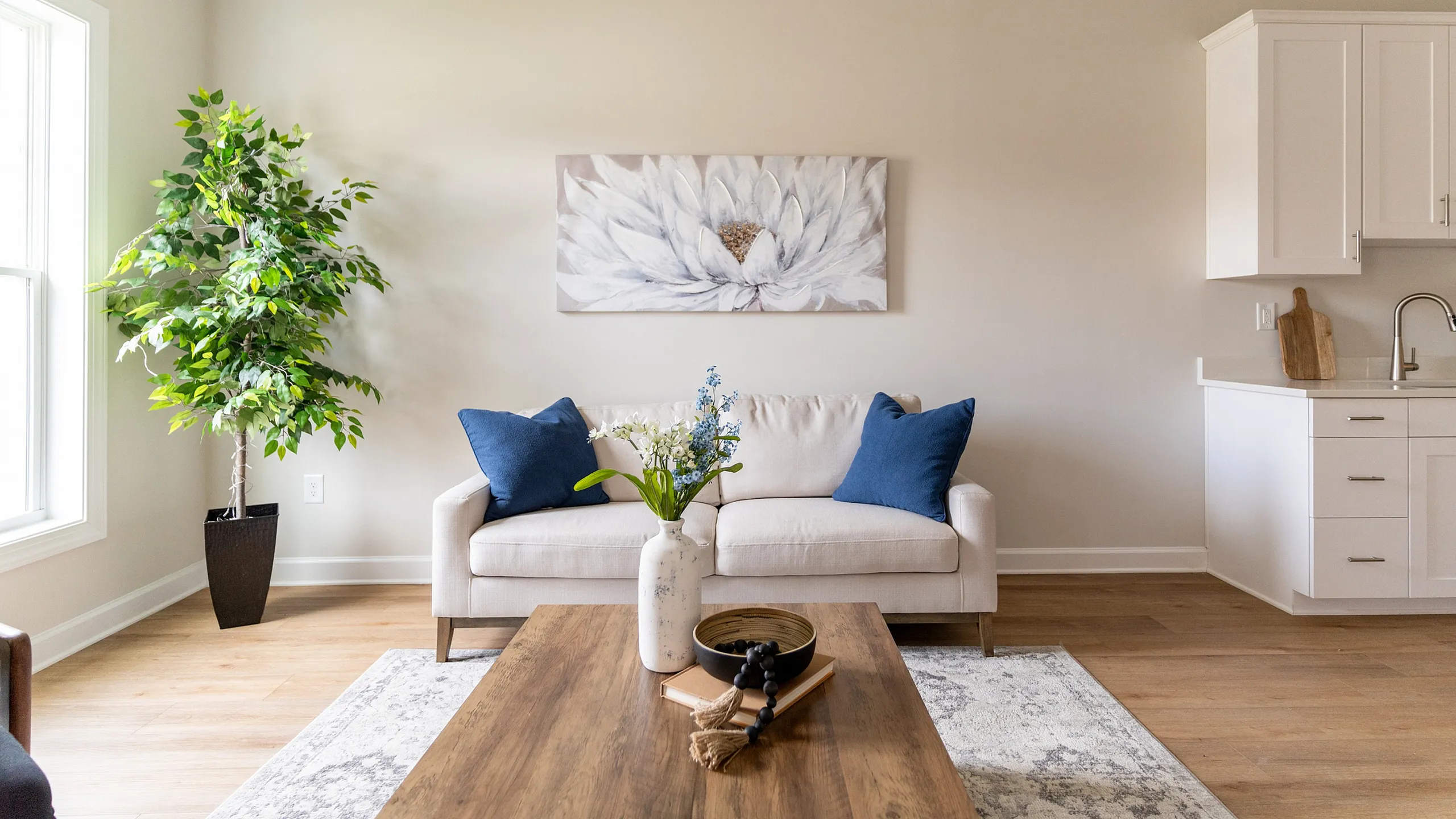 Bright and inviting living room with a cozy sofa, elegant artwork, and vibrant greenery, offering a modern and stylish ambiance.
