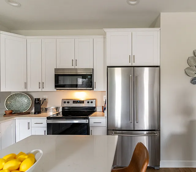 Sleek modern kitchen featuring stainless steel appliances, elegant white cabinetry, and a stylish countertop with a bowl of fresh lemons.