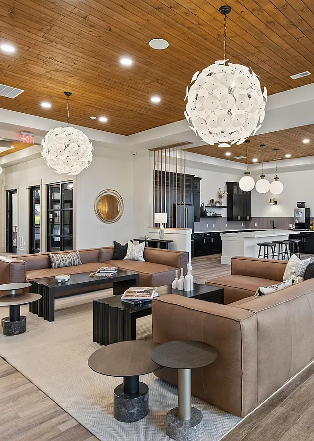 Luxurious open-concept living area with modern decor, leather seating, and elegant lighting, featuring a stylish kitchen in the background.