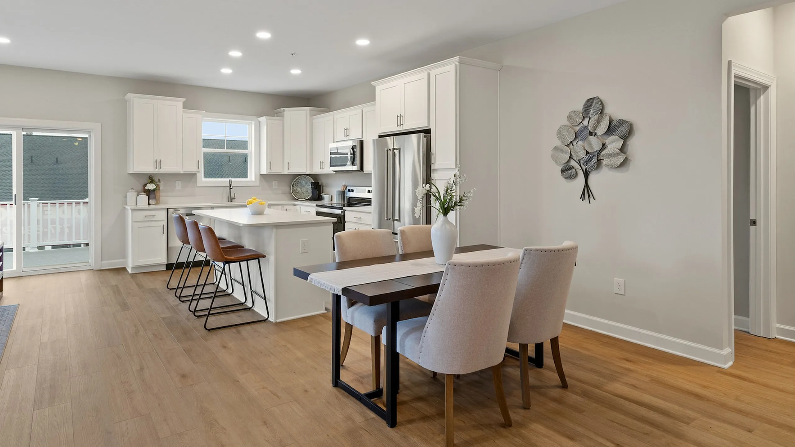 Modern open-concept kitchen and dining area with elegant white cabinetry, wood flooring, and abundant natural light.