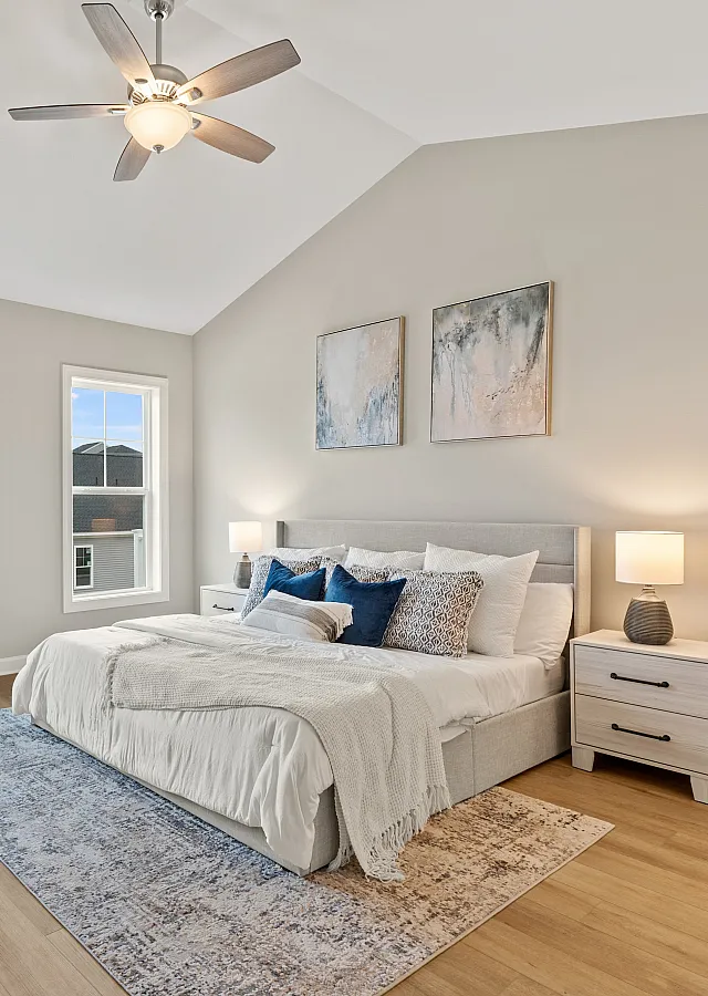 Bright and airy bedroom with stylish decor, featuring a plush bed, elegant ceiling fan, and contemporary furnishings.