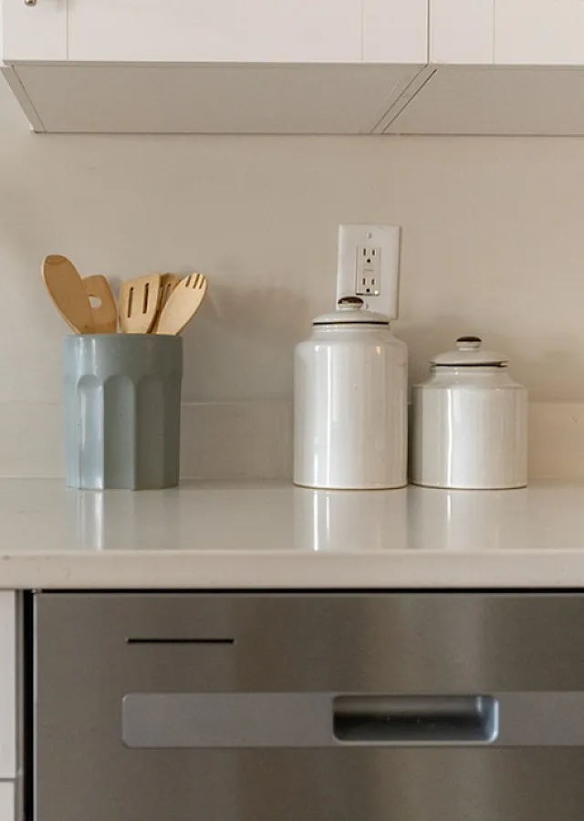 Modern kitchen with sleek stainless steel appliances, elegant white cabinetry, and stylish countertop accessories.