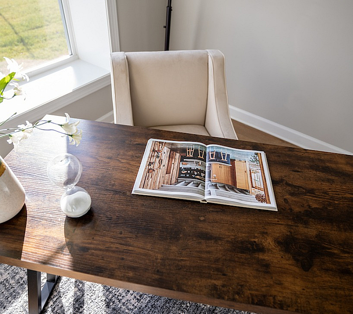 Inviting study area with a rustic wooden desk, elegant chair, and vibrant floral decor, bathed in natural light.