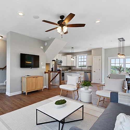 Bright and modern open-concept living area with elegant hardwood floors, stylish lighting, and a contemporary kitchen featuring stainless steel appliances.