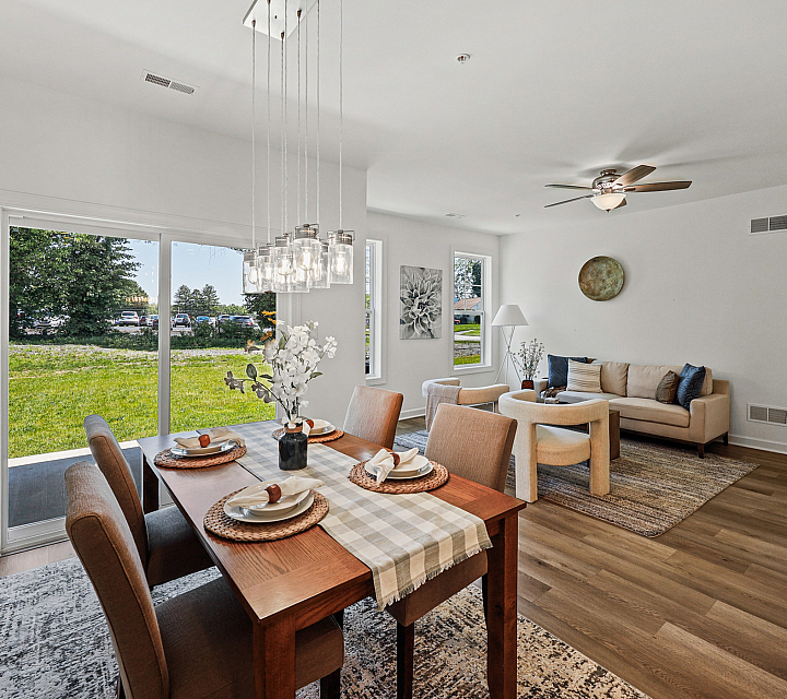 Charming open-concept living and dining area featuring elegant decor, abundant natural light, and picturesque outdoor views.