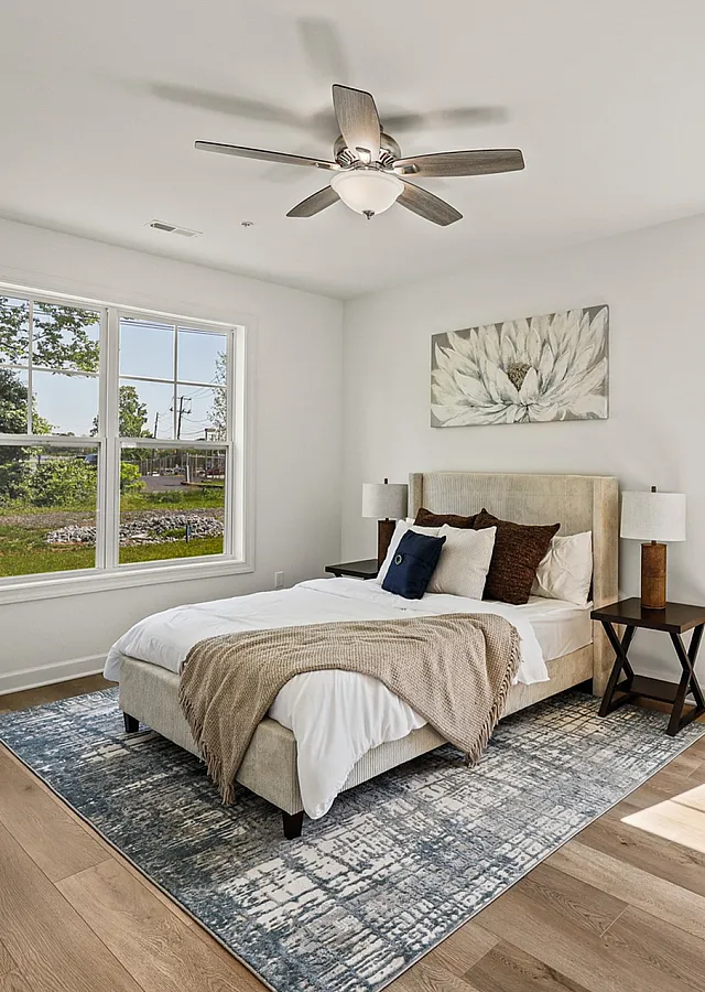 Bright and inviting bedroom with elegant decor, large windows, and beautiful hardwood flooring.