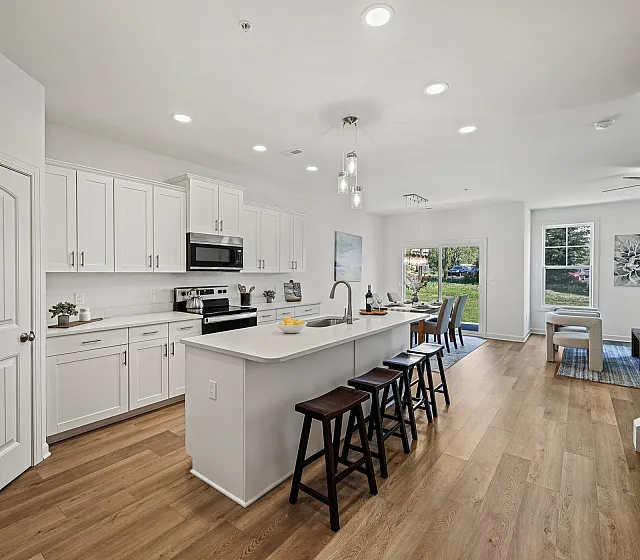 Contemporary open-concept kitchen and dining area with sleek white cabinetry, a stylish island with seating, and elegant hardwood floors.