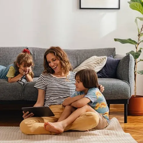 Warm and inviting living room with a joyful family enjoying quality time together, featuring a comfortable sofa, lush greenery, and abundant natural light.