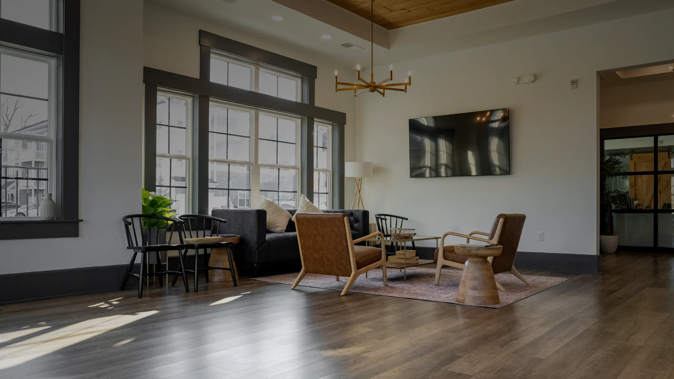 Bright and inviting living room with modern furnishings, large windows, and wooden flooring, perfect for relaxation and entertainment.