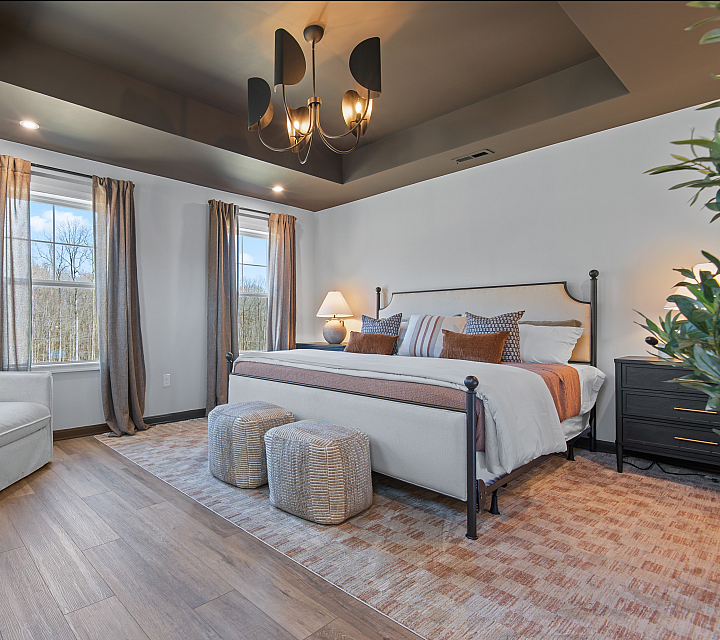 Elegant bedroom featuring a cozy king-sized bed, stylish chandelier, and large windows with scenic views, offering a serene retreat.