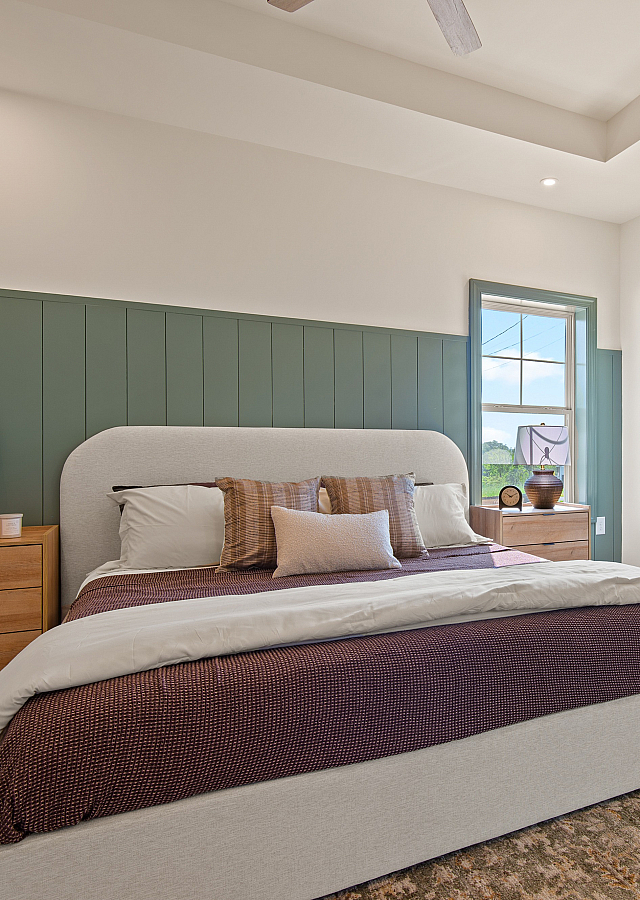 Inviting bedroom with a cozy bed, stylish wooden furniture, and abundant natural light through large windows, creating a serene and comfortable living space.