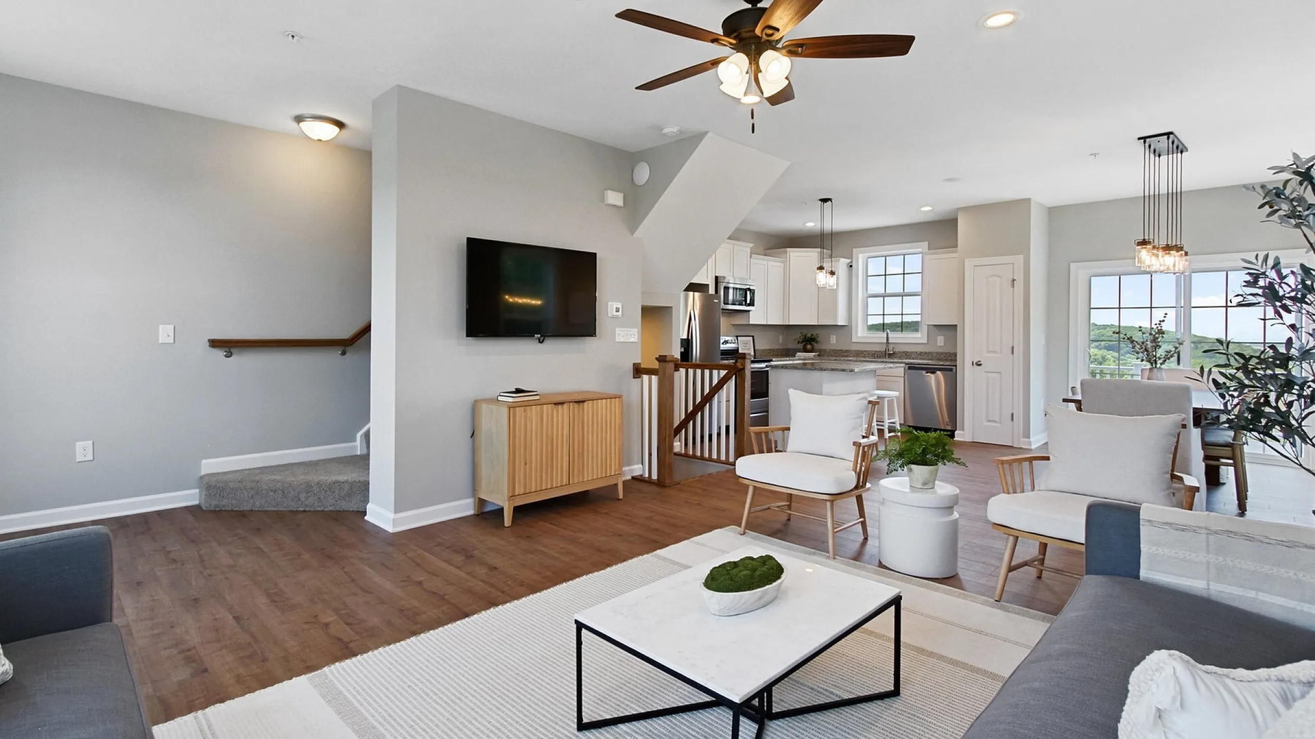 Contemporary open-plan living room with elegant furniture, chic kitchen, and serene views from expansive windows.