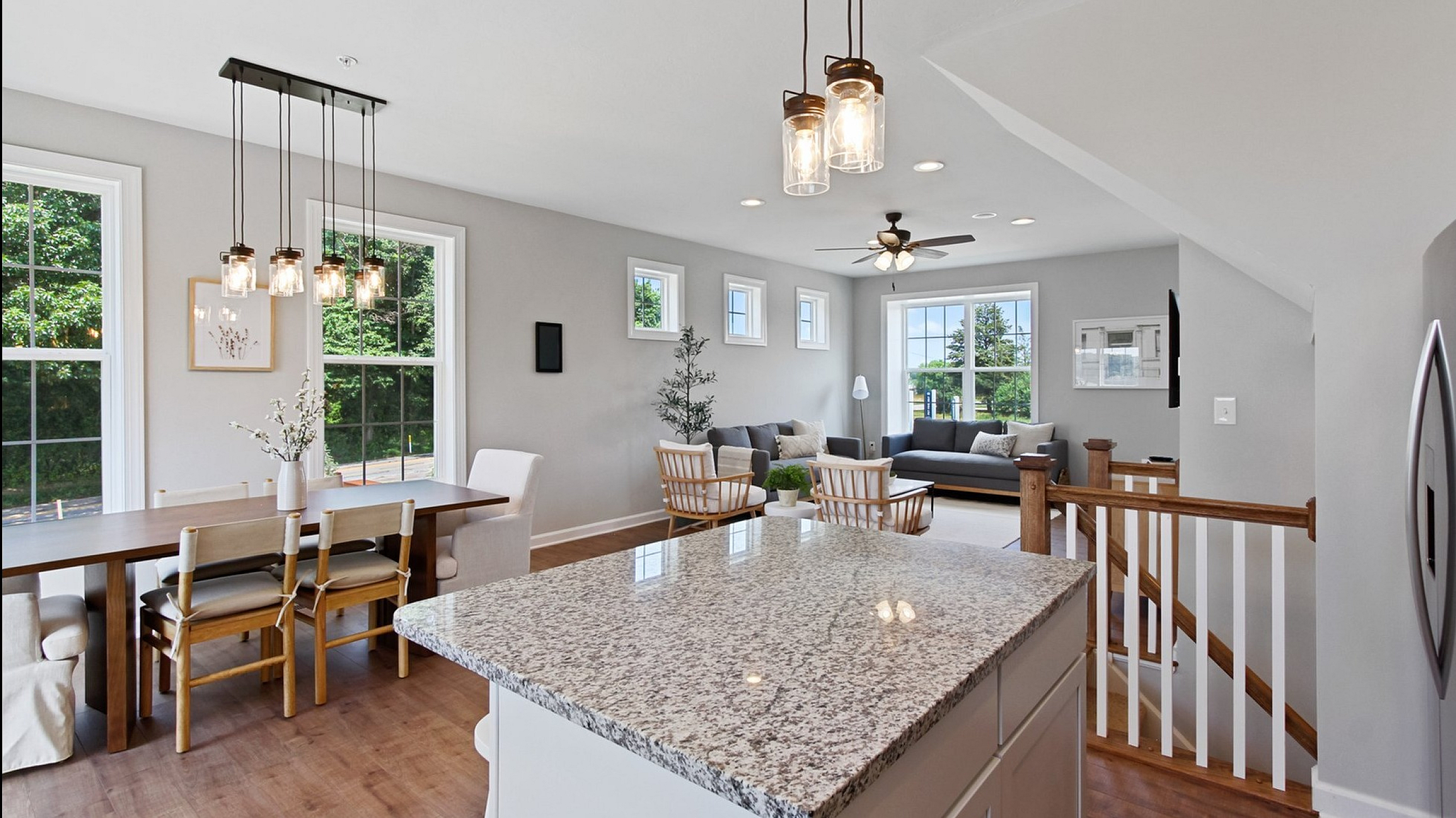 Bright and modern open-plan living space with large windows, elegant kitchen island, cozy seating area, and stylish dining table.