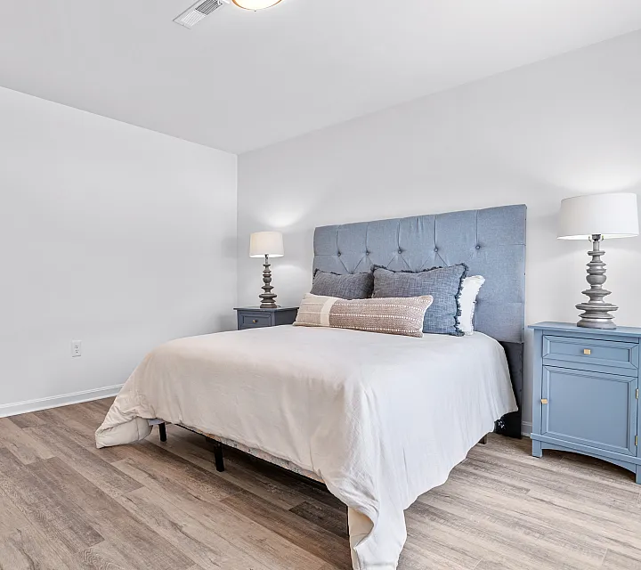 Bright and airy bedroom with modern decor, featuring a plush bed with a stylish headboard, elegant lighting, and cozy wooden flooring.