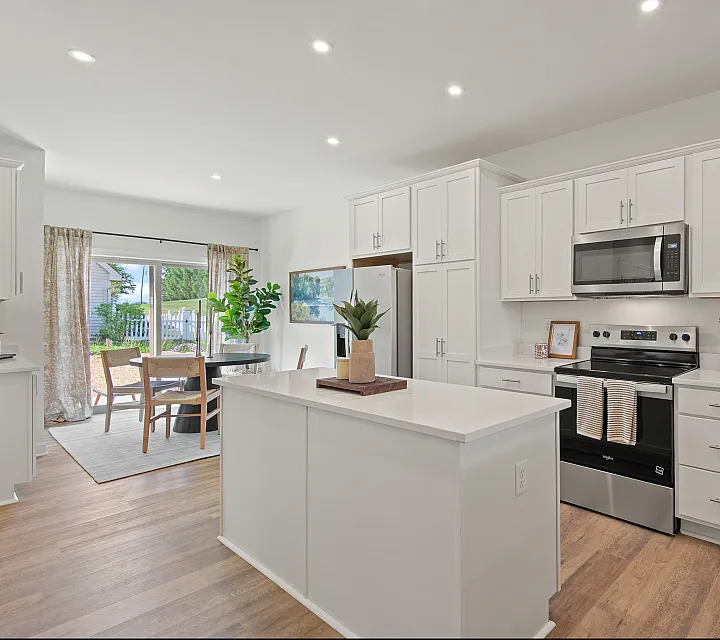 Bright and modern kitchen with sleek white cabinetry, stainless steel appliances, and an inviting dining area overlooking a lush garden.