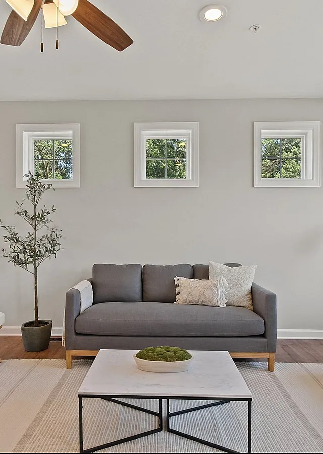 Bright and inviting living room with modern gray sofas, a chic marble coffee table, and abundant natural light from large windows.
