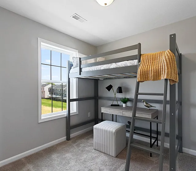 Bright bedroom featuring a stylish loft bed with ladder, a cozy workspace beneath, and a large window with scenic views.