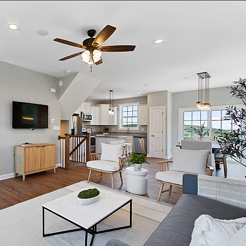 Bright and spacious open-concept living room with elegant furniture, contemporary kitchen, and large windows offering a picturesque view.