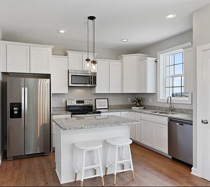 Bright modern kitchen featuring granite countertops, stainless steel appliances, and elegant white cabinetry with a breakfast bar.