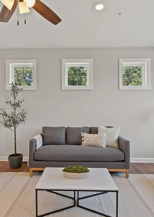 Bright and modern living room with stylish gray sofas, elegant lighting, and calming natural d&eacute;cor beside large sunlit windows.