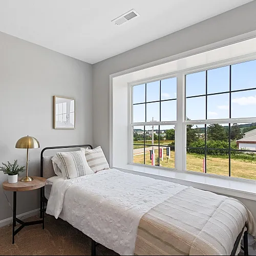 Bright and cozy bedroom with a large window offering scenic views, featuring a stylish bed and elegant decor.