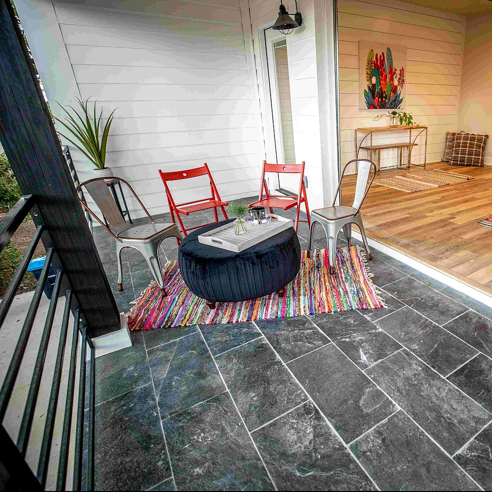 Charming apartment with inviting patio and stylish interior. Features a cozy outdoor seating area with vibrant chairs and table, seamlessly flowing into a warm wooden-floored living room full of natural light.