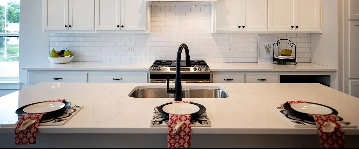 Modern kitchen with elegant white cabinetry, sleek black pendant lighting, and a stylish island featuring a farm-style sink.