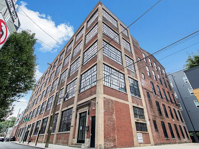 Charming red-brick building with large industrial-style windows, offering unique urban living spaces with a historic touch.