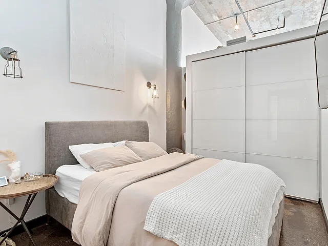 Modern bedroom with a sleek design, featuring a cozy bed, minimalist decor, and bright natural lighting.