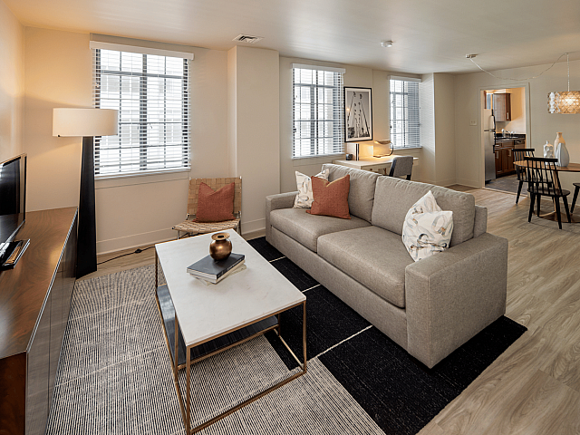 Inviting living room with modern decor, ample natural light, cozy sofa, and stylish open-concept dining area.