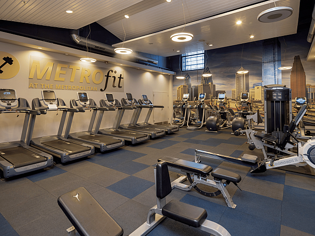 Modern fitness center showcasing state-of-the-art treadmills, elliptical machines, and vibrant cityscape mural, perfect for an energetic workout.