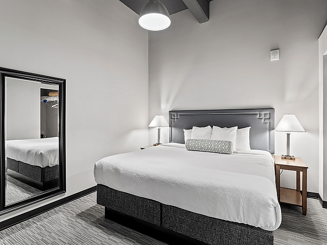 Elegant bedroom featuring a plush king-size bed, modern lighting, and a stylish full-length mirror.