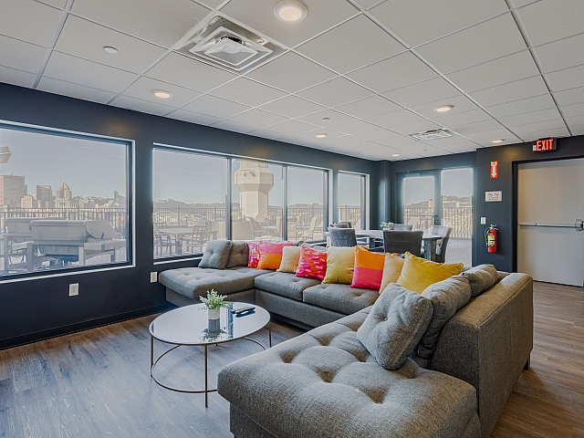 Sophisticated living room with panoramic city views, featuring a plush sectional sofa and vibrant decor, ideal for relaxation and entertainment.