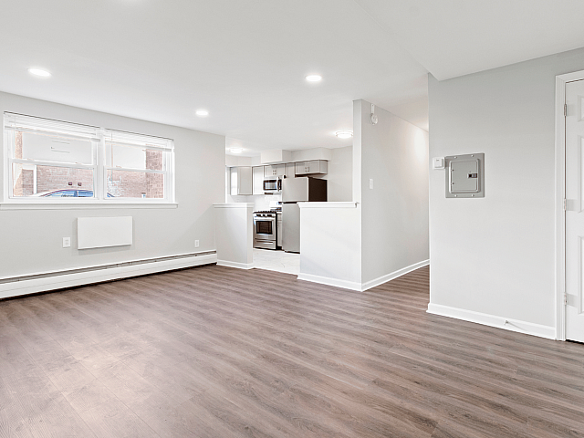 Bright open-concept living space with elegant hardwood floors and a modern kitchen featuring sleek stainless steel appliances.