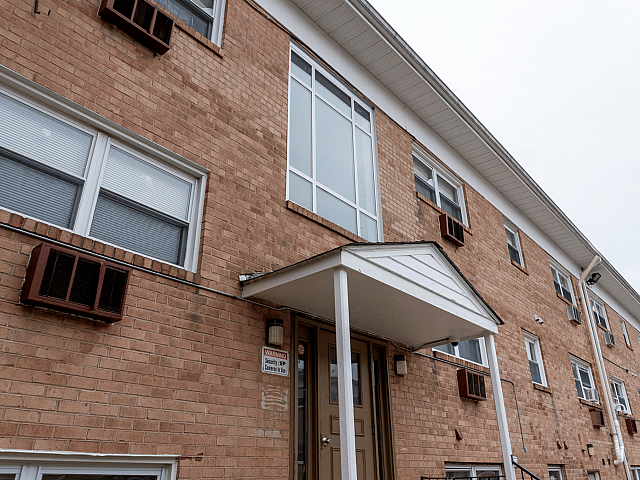 Charming brick apartment building with large windows and a welcoming entrance, ideal for urban living.