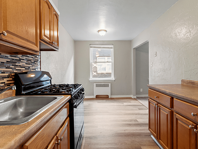 Modern kitchen with sleek wooden cabinetry, elegant tiled backsplash, and large window offering natural light.