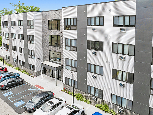 Modern apartment building exterior showcasing sleek design, ample parking, and vibrant landscaping.